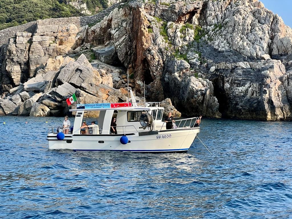 Una barca galleggia sulla superficie di uno specchio d'acqua di fronte a una scogliera rocciosa.