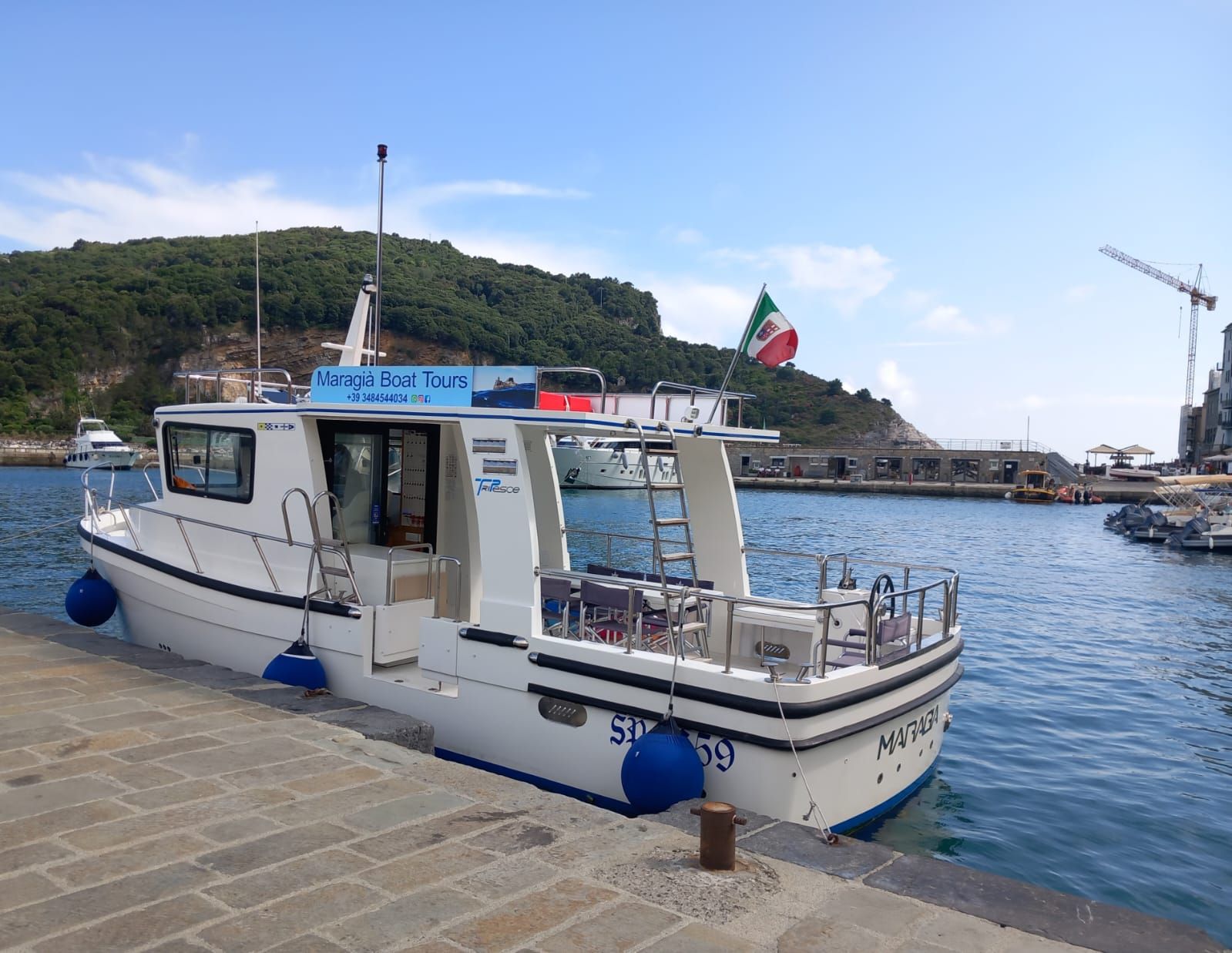 Una piccola barca bianca è attraccata in un porto.