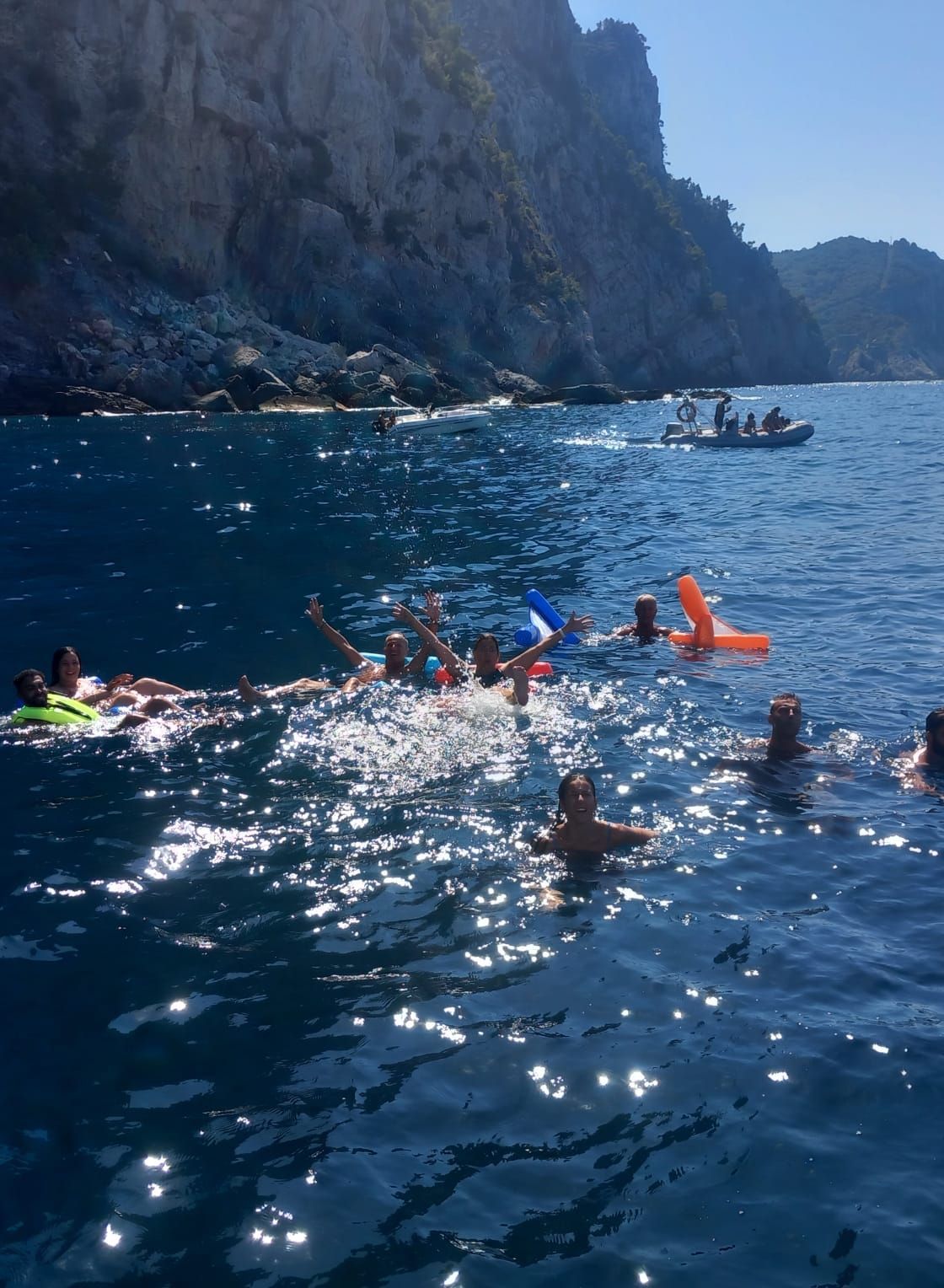 Un gruppo di persone sta nuotando nell'oceano con una barca sullo sfondo