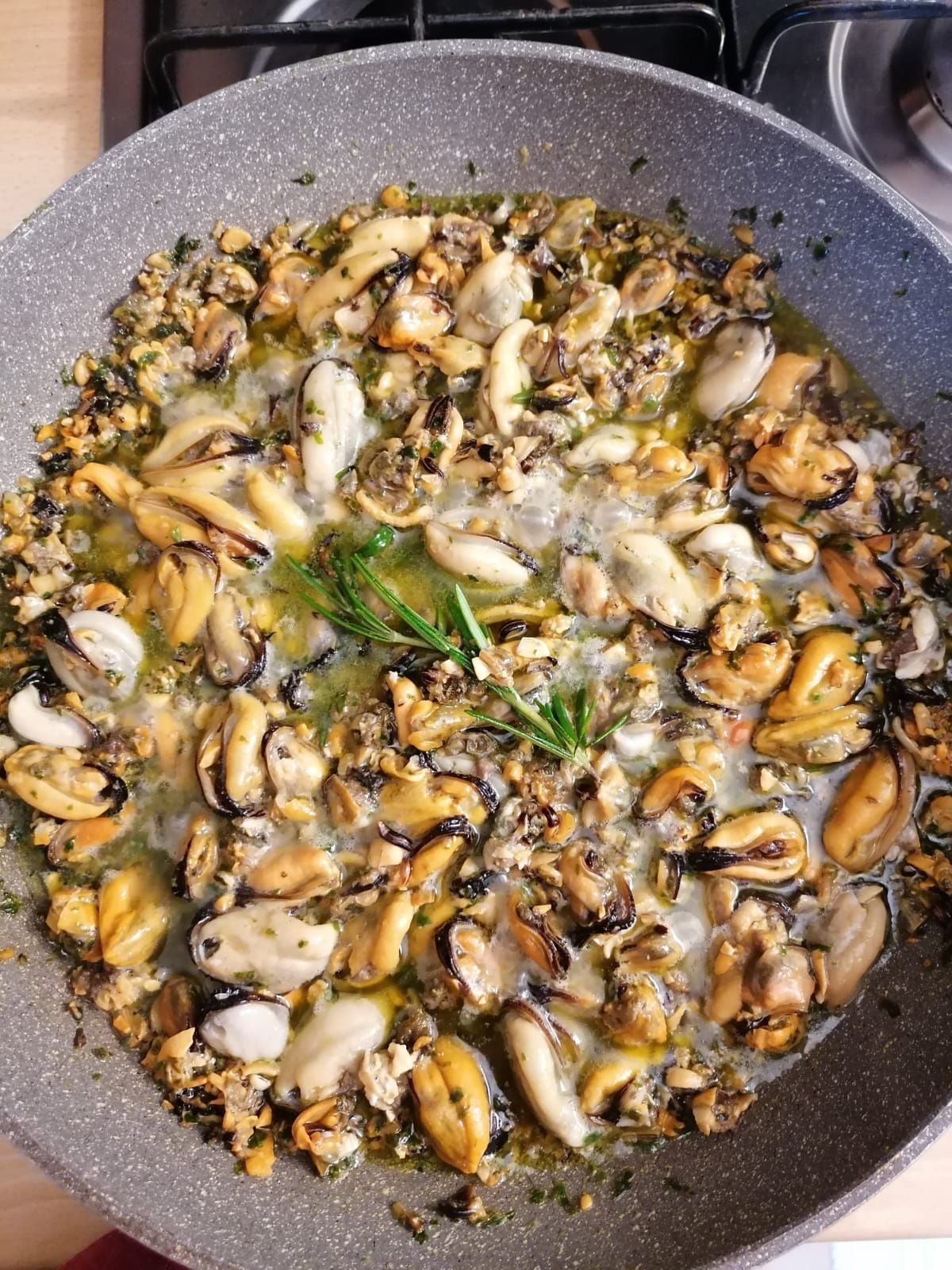 Le cozze vengono cucinate in una padella sul fornello.