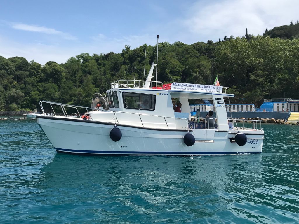 Una piccola barca bianca galleggia sulla superficie di uno specchio d'acqua.