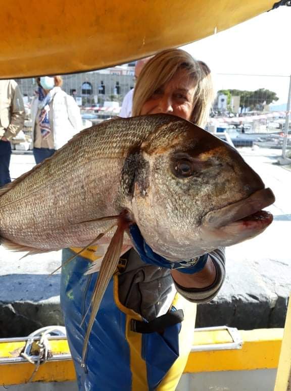 Una donna tiene in mano un grosso pesce
