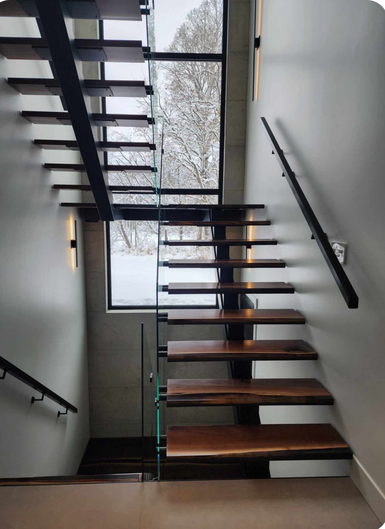 Un escalier avec des marches en bois et une rampe en verre