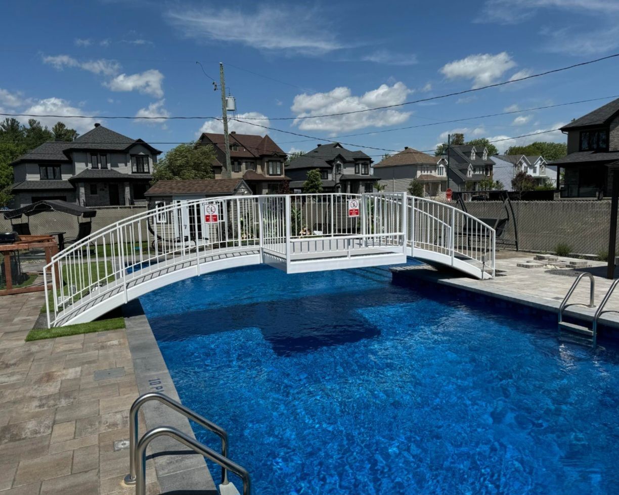Il y a un petit pont au dessus d'une piscine.