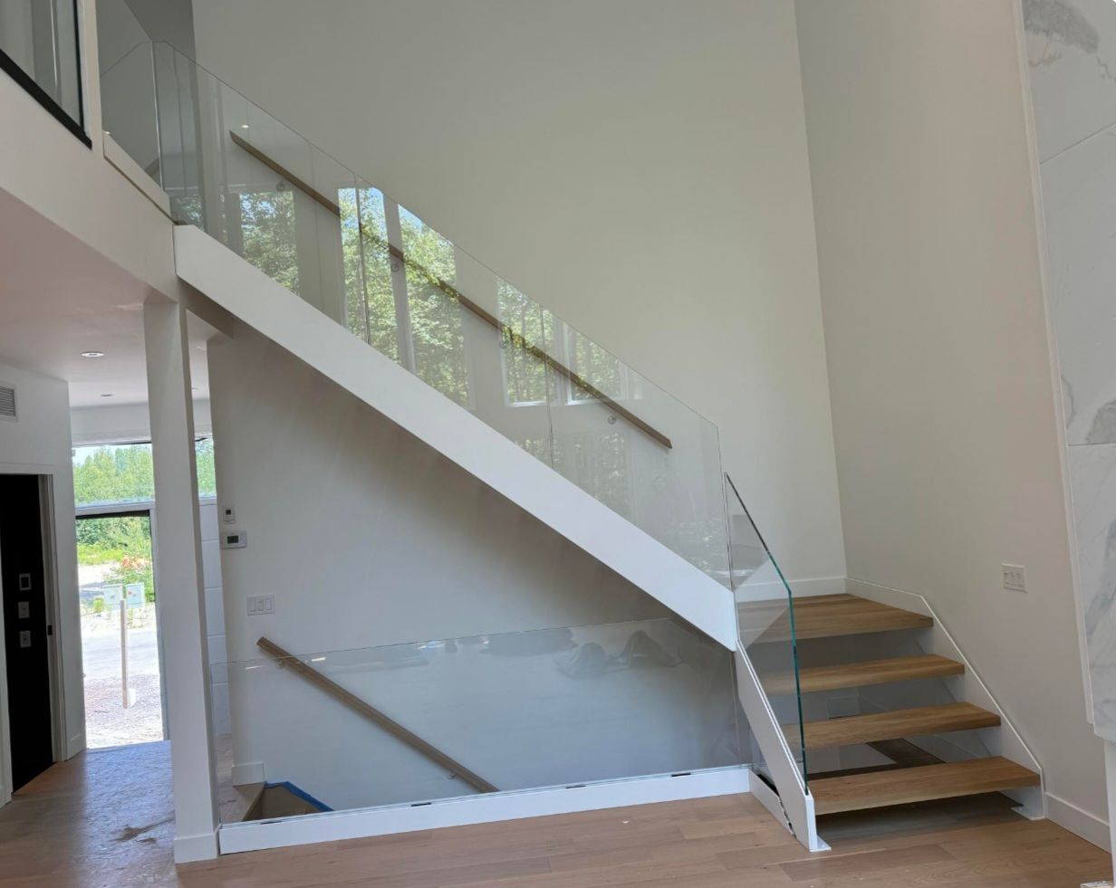 Un escalier en bois avec une rampe en verre dans une maison.