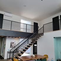 Un salon avec un escalier et une table et des chaises.