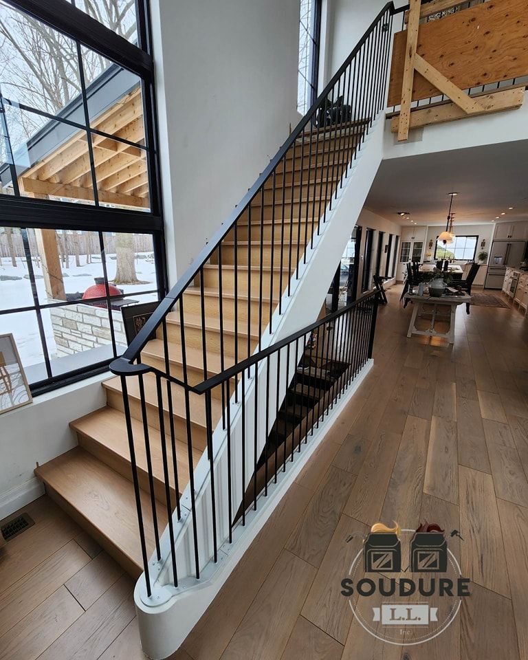 Un escalier en bois avec une rampe noire dans une maison.