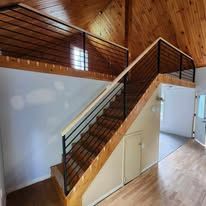 Un escalier en bois avec une rampe en métal dans une maison.