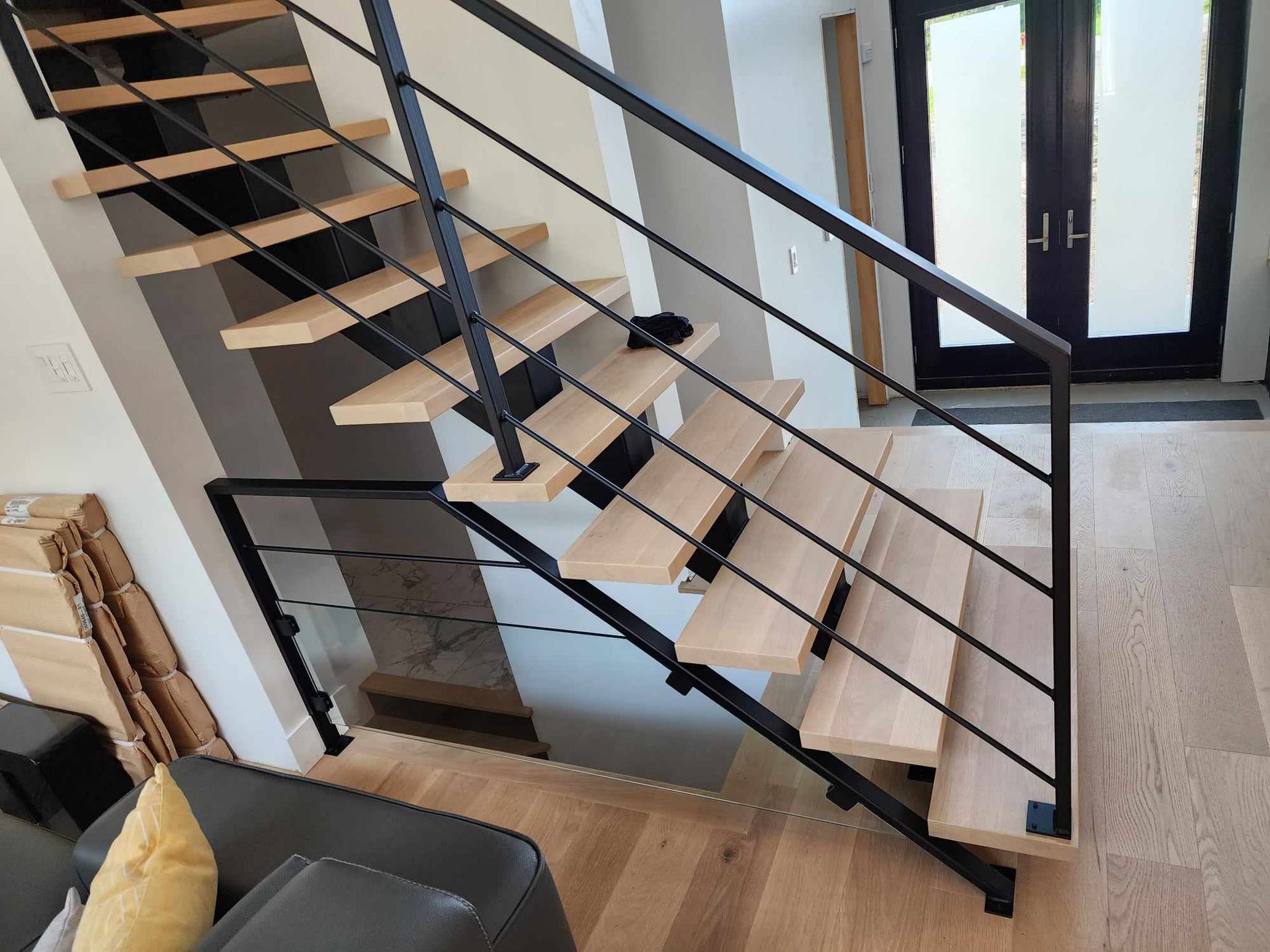 A wooden staircase with a black railing in a living room