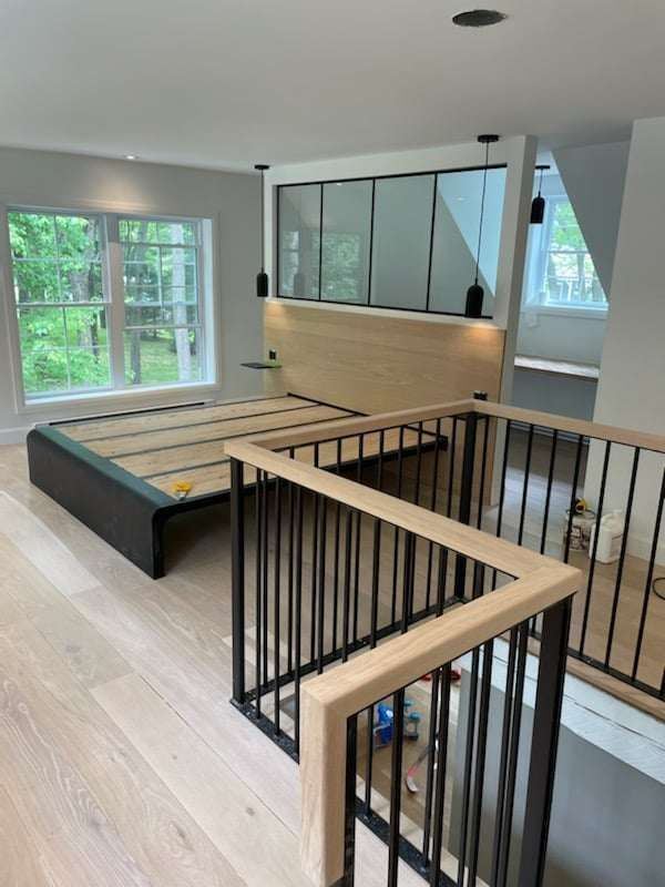 A bedroom with a bed and a balcony with a railing.