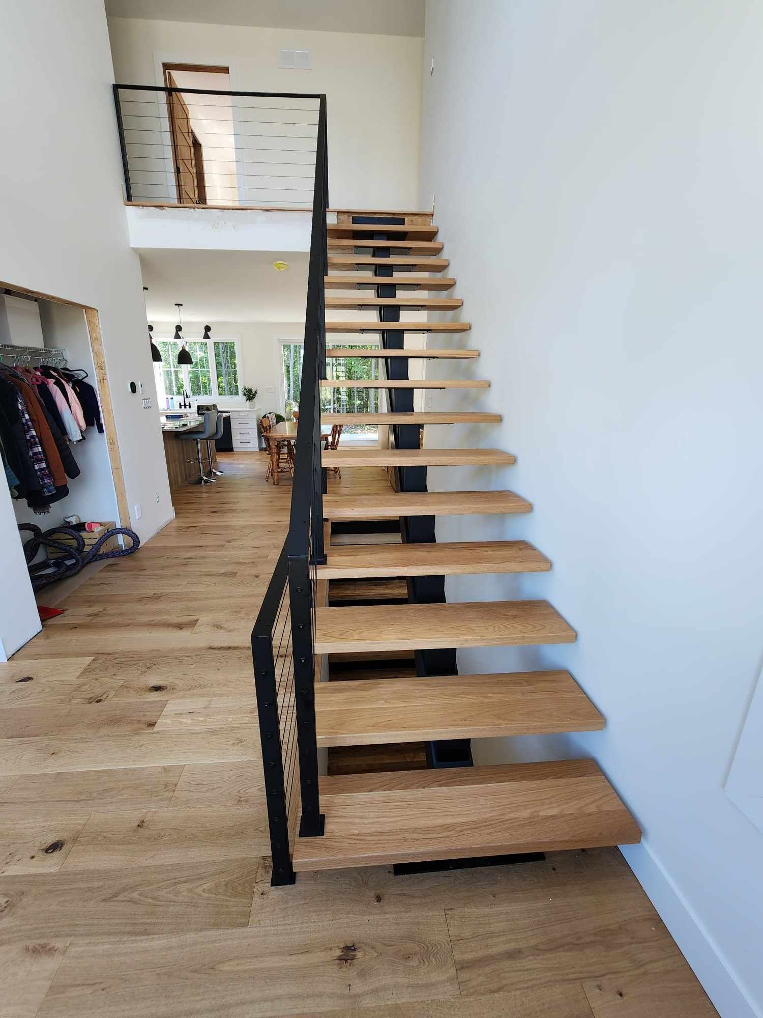 A wooden staircase with a metal railing in a hallway leading to a second floor.