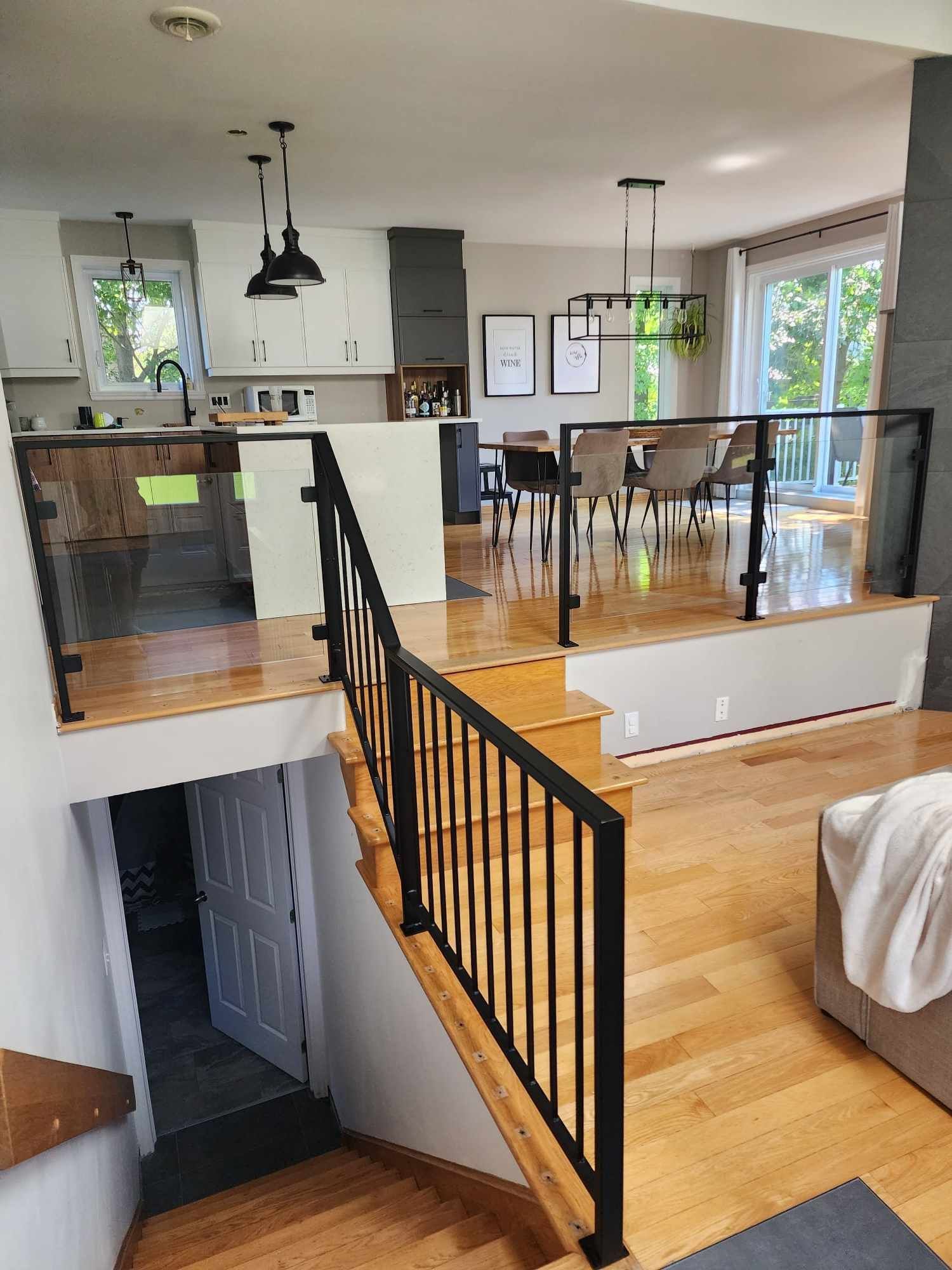 A living room with stairs leading up to a dining room and kitchen.