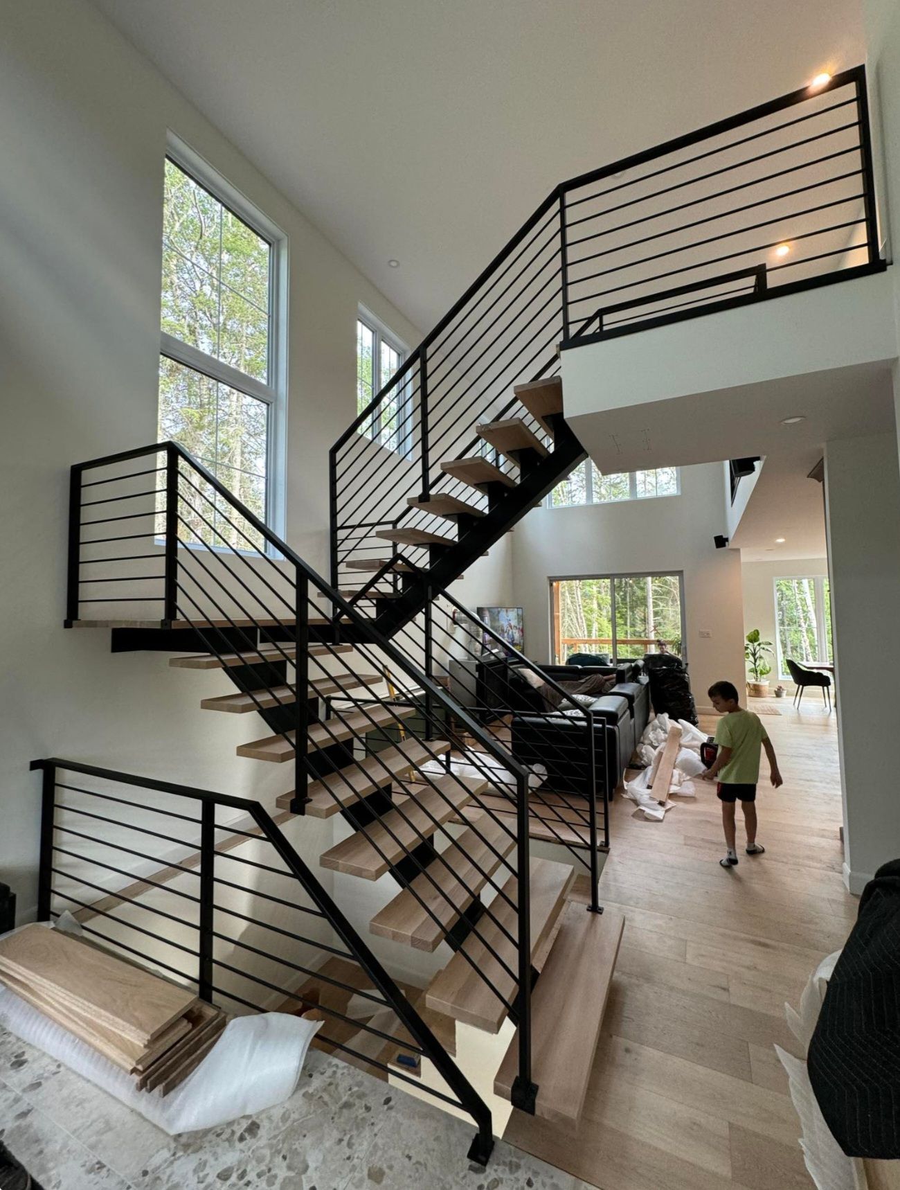 Un escalier dans une maison avec une rampe noire et des marches en bois.