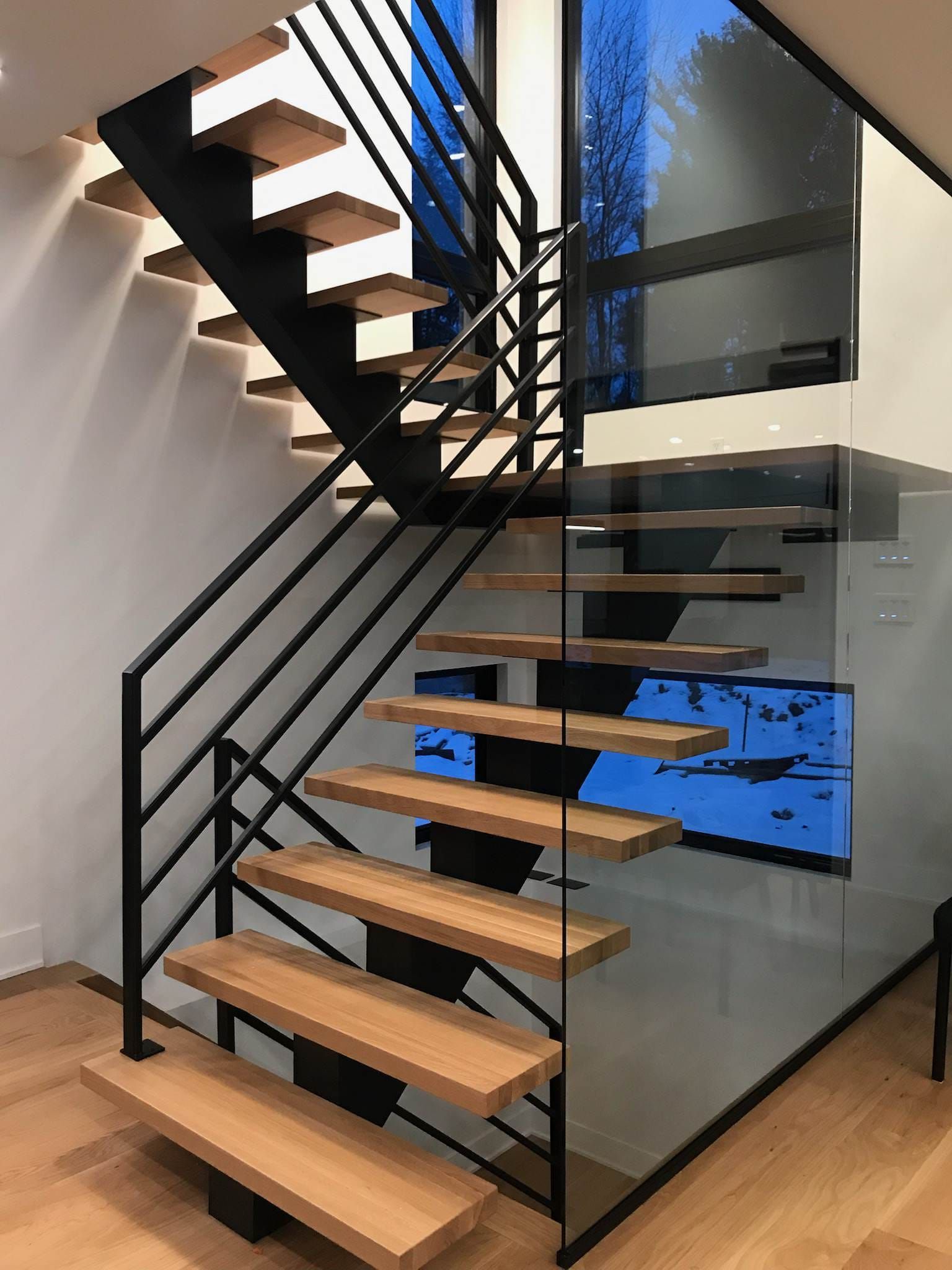 Un escalier moderne avec des marches en bois et une rampe en verre