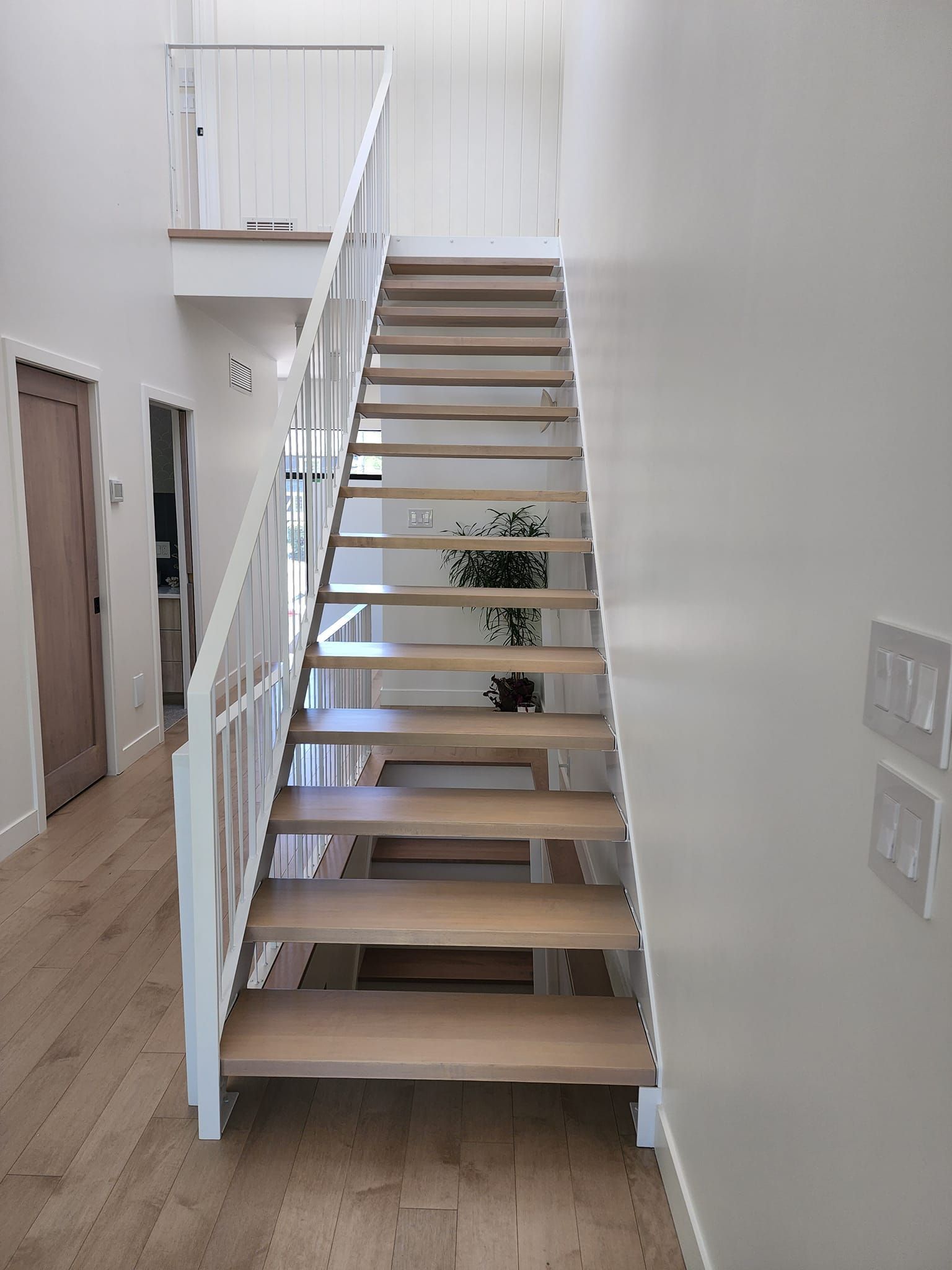 Un escalier en bois avec une rampe blanche dans un couloir.
