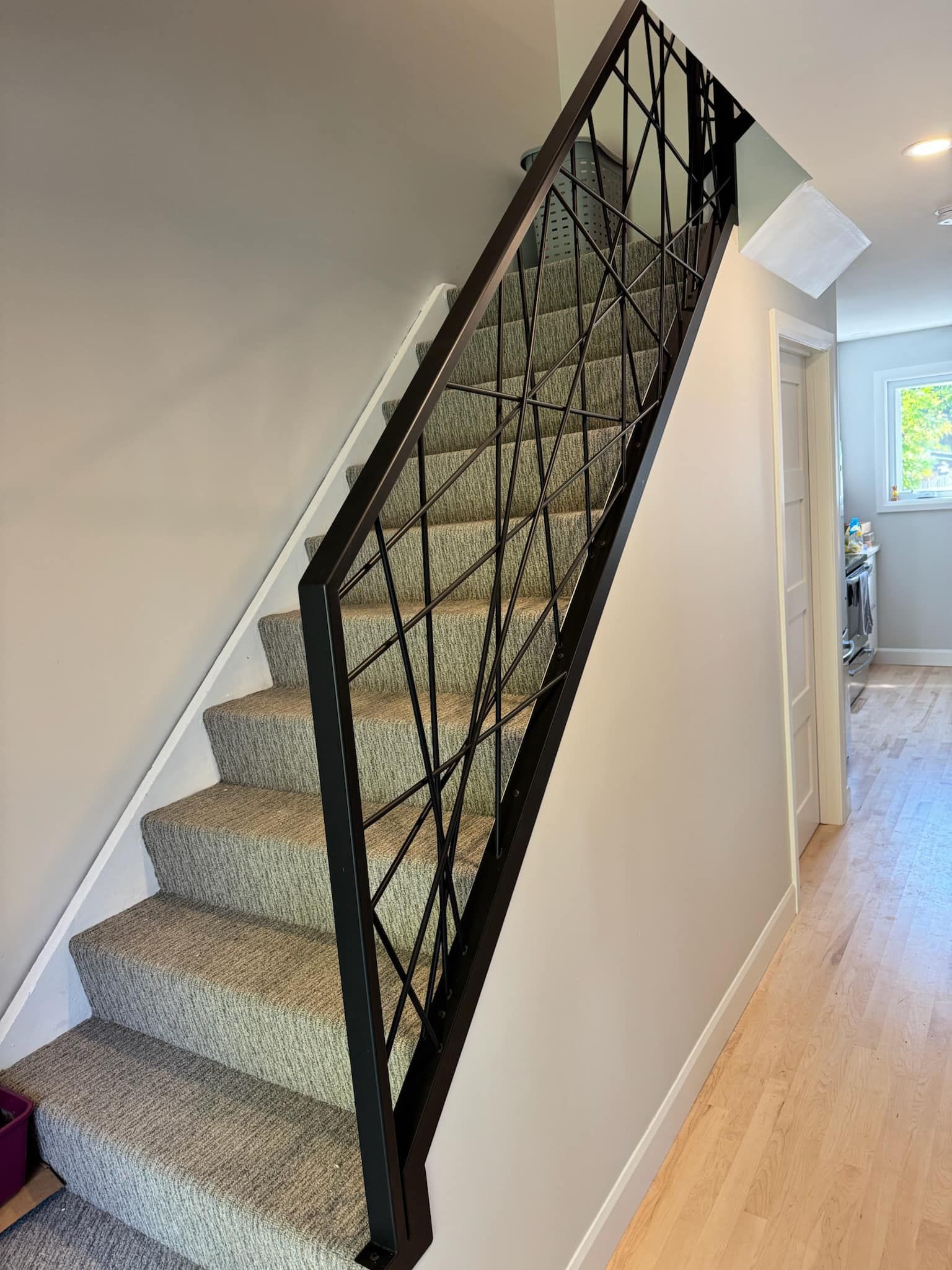 Un escalier avec une rampe en fer forgé et des marches recouvertes de moquette dans un couloir.