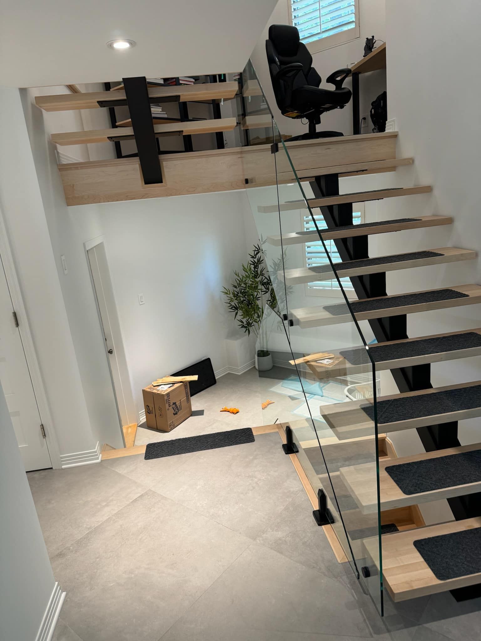 Un escalier en bois avec une rampe en verre dans une maison.