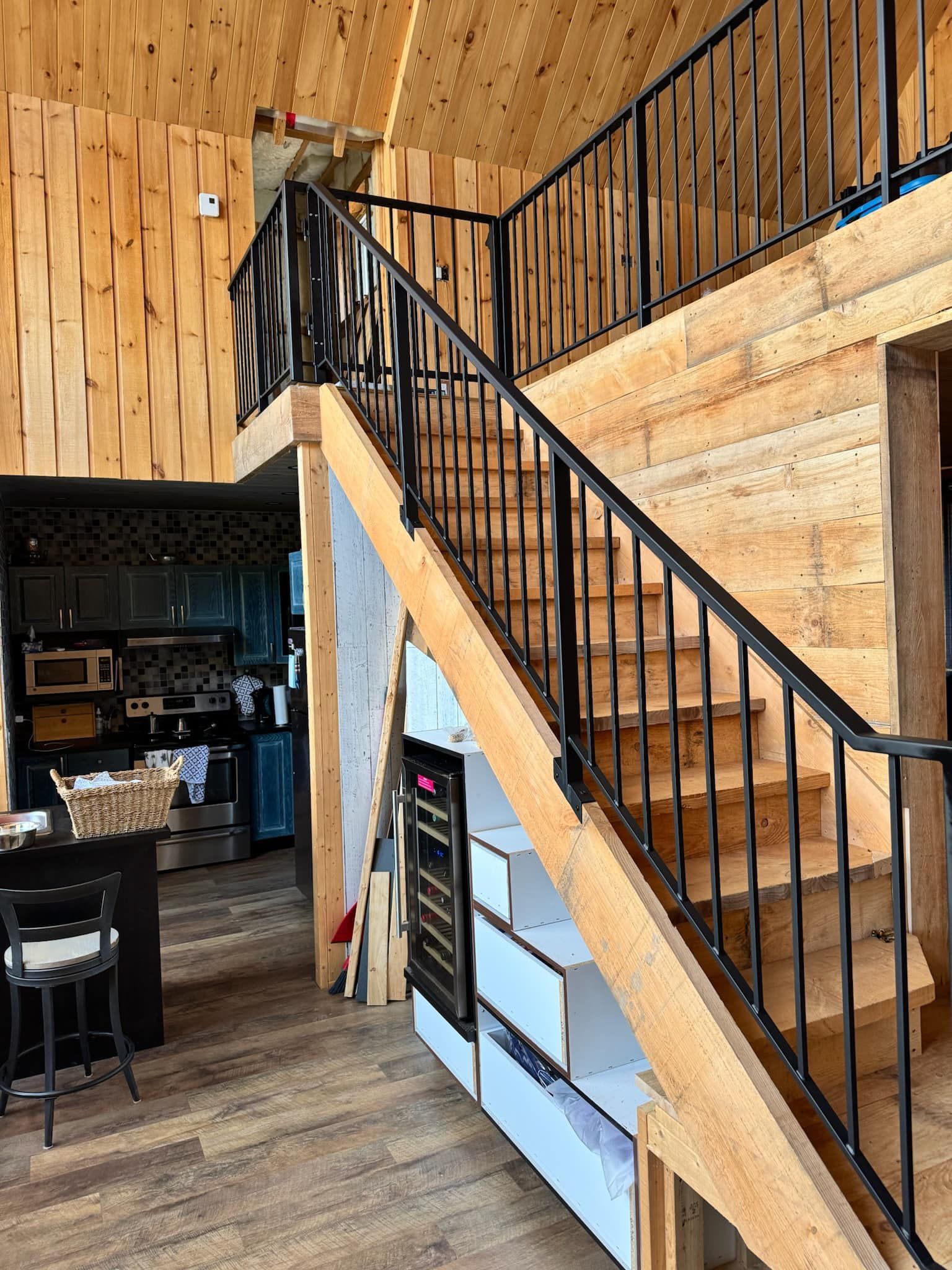 Un escalier en bois avec une rampe en métal menant au deuxième étage d'une maison.