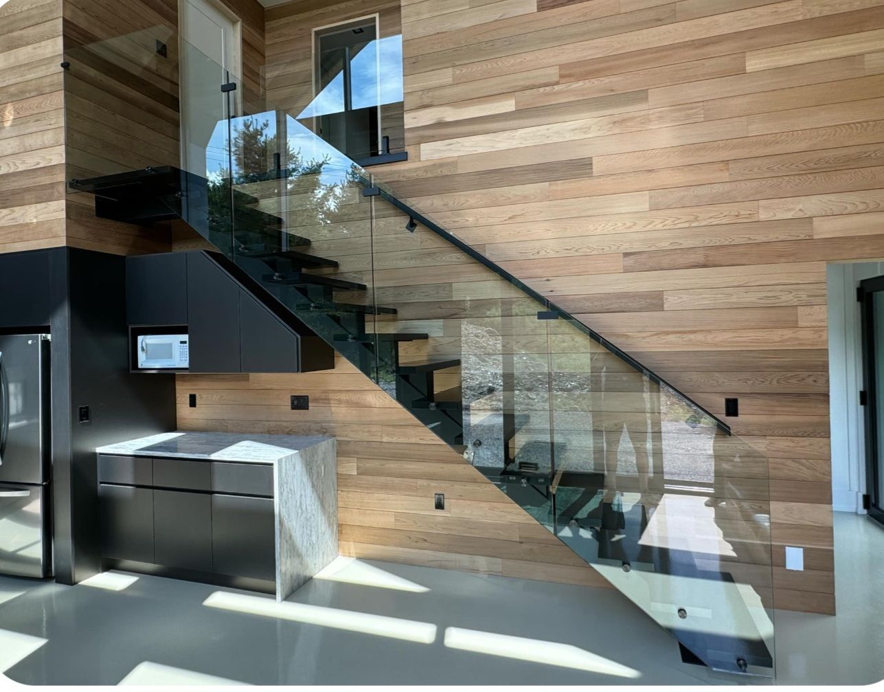 Un escalier moderne avec une rampe en verre dans une maison.