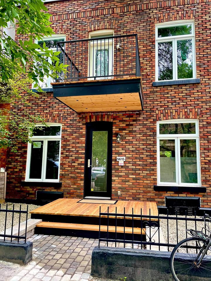 A brick building with a balcony and a bicycle parked in front of it.