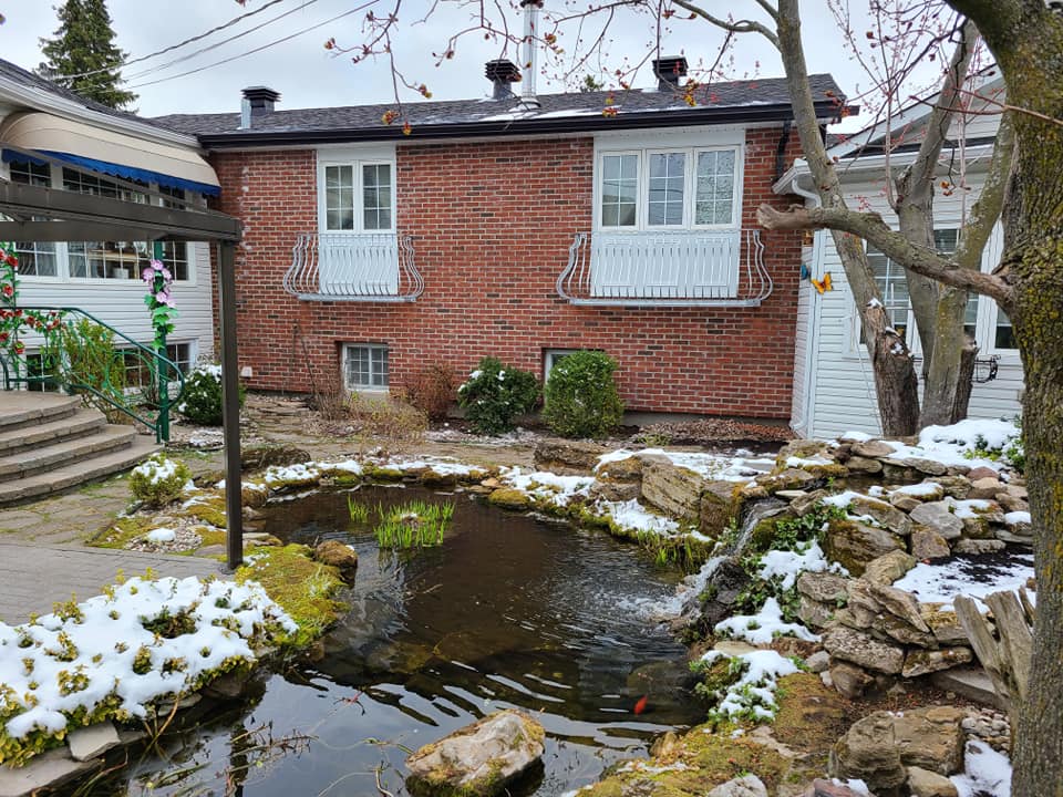 A brick house with a pond in front of it.