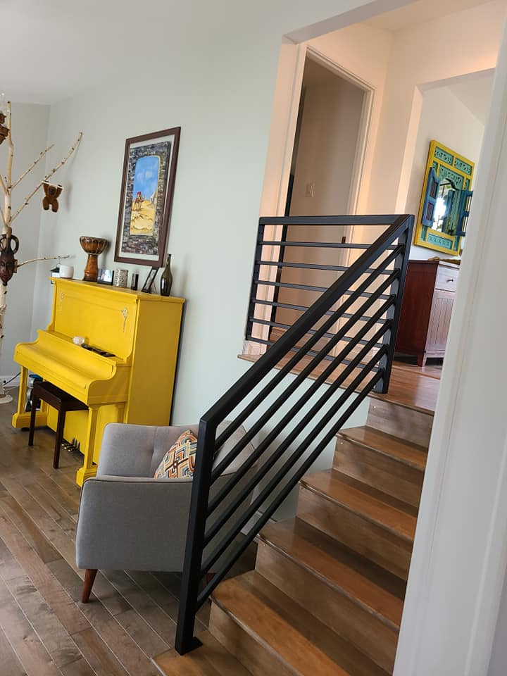A living room with a yellow piano and stairs