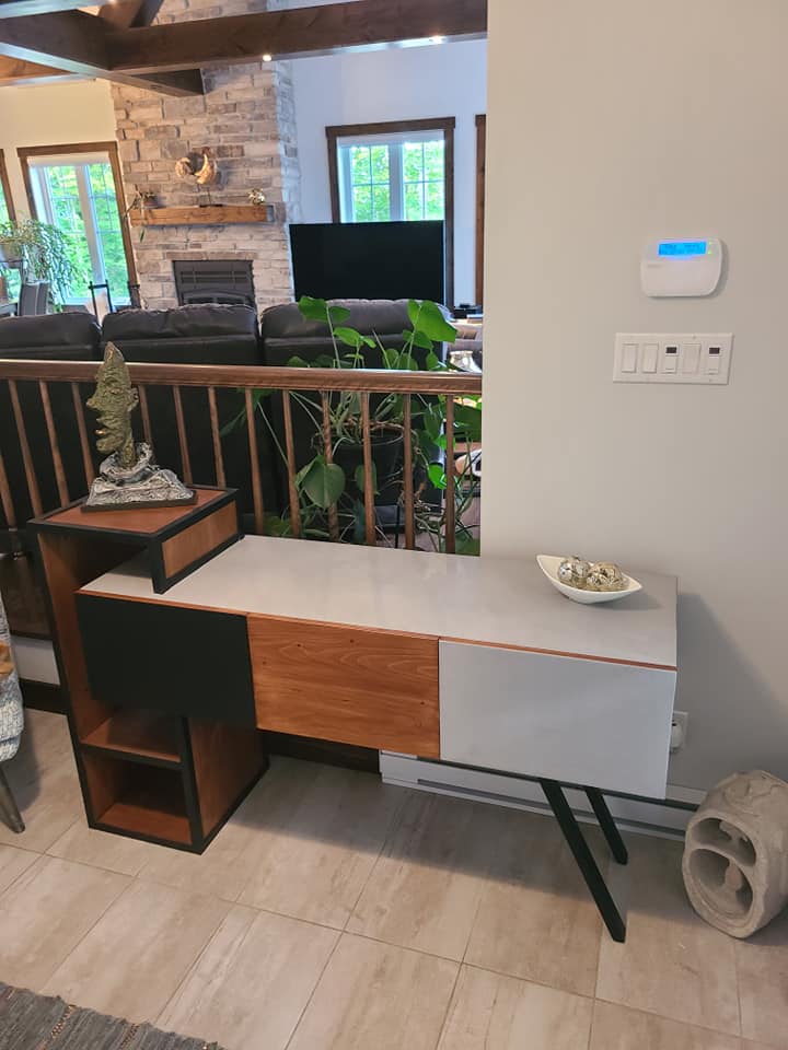A living room with a table and a thermostat on the wall.