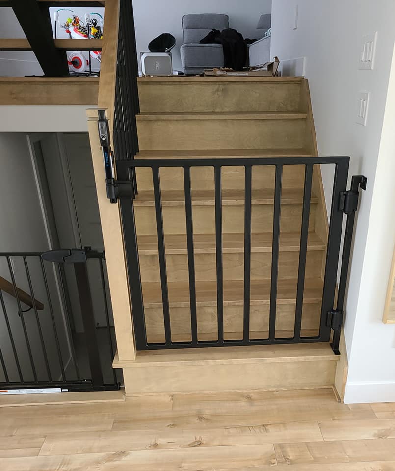 A wooden staircase with a metal railing and a gate