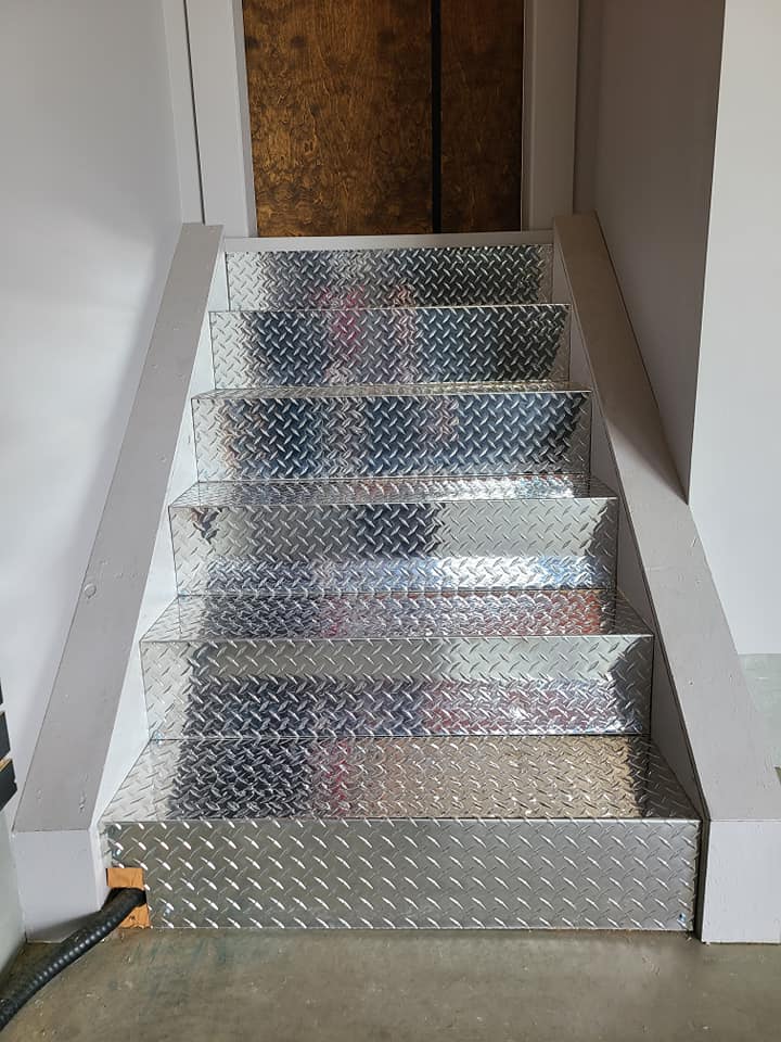 A set of stairs made of aluminum in a basement.