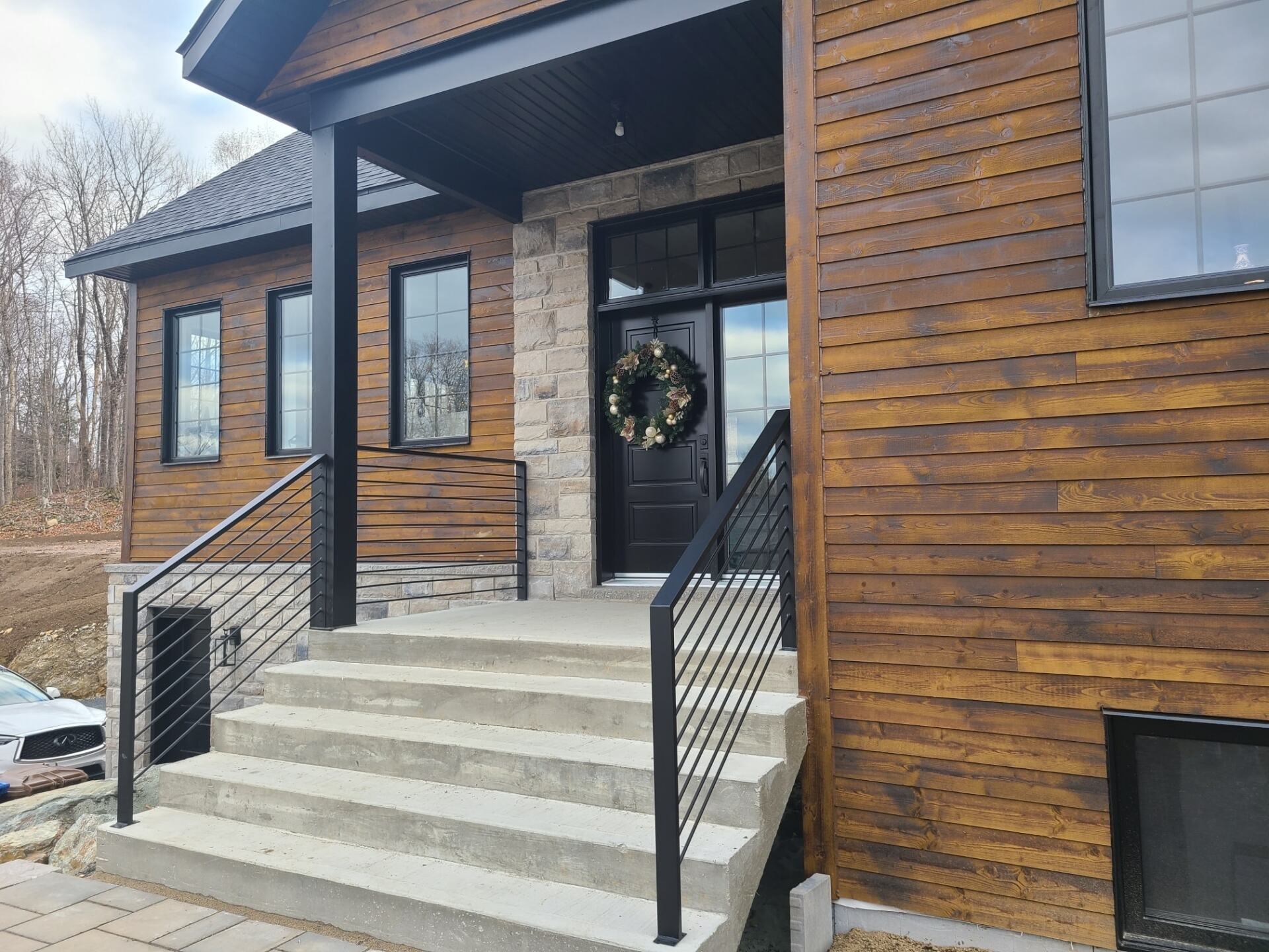 The front of a house with a wreath on the door and stairs leading up to it.