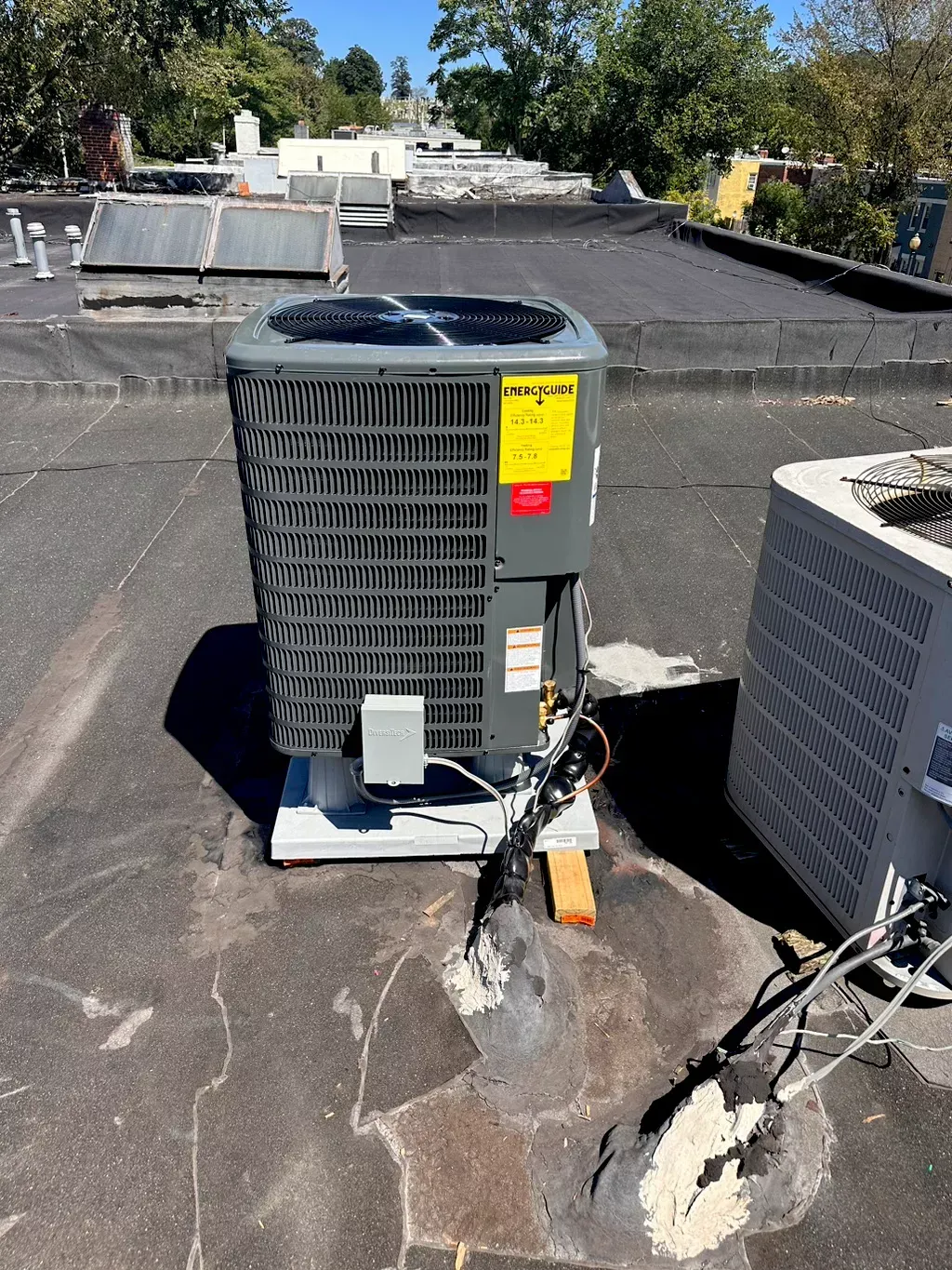 HVAC unit on a flat roof. Black roof with gray air conditioning unit. Yellow energy label.