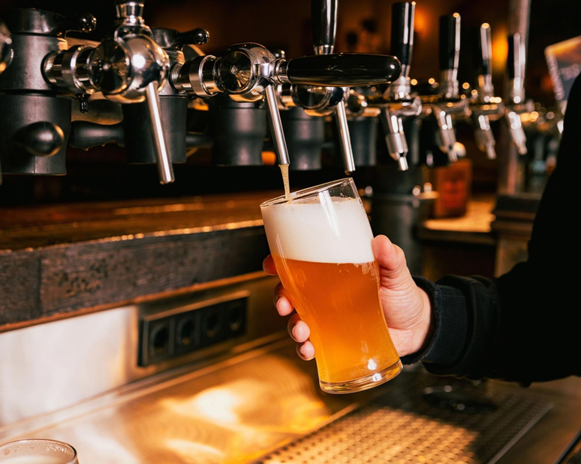 A person is pouring beer into a glass at a bar