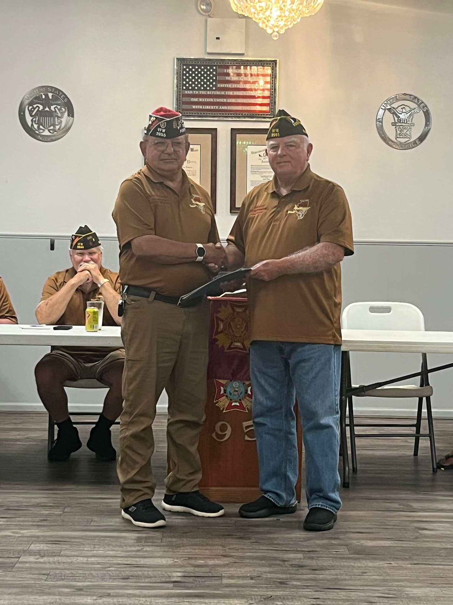 Two men in military uniforms are shaking hands in a room.