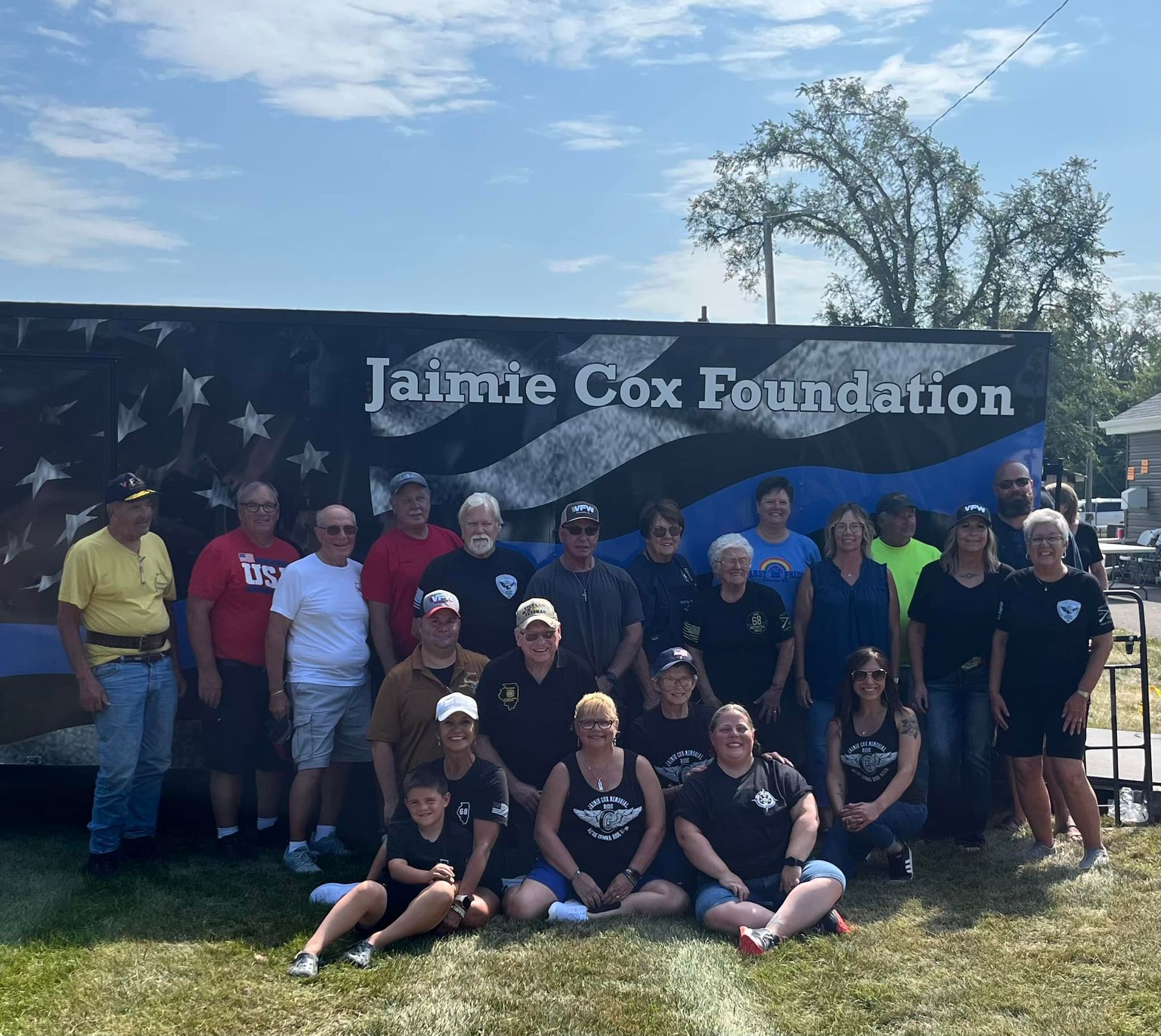 A group of people posing in front of a jaime cox foundation sign