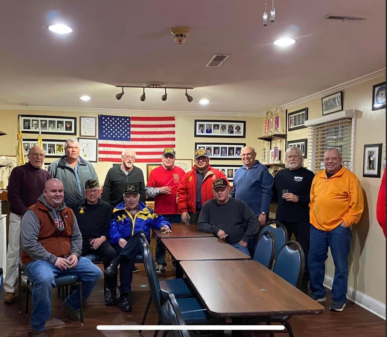 A group of men are posing for a picture in a room with tables and chairs.
