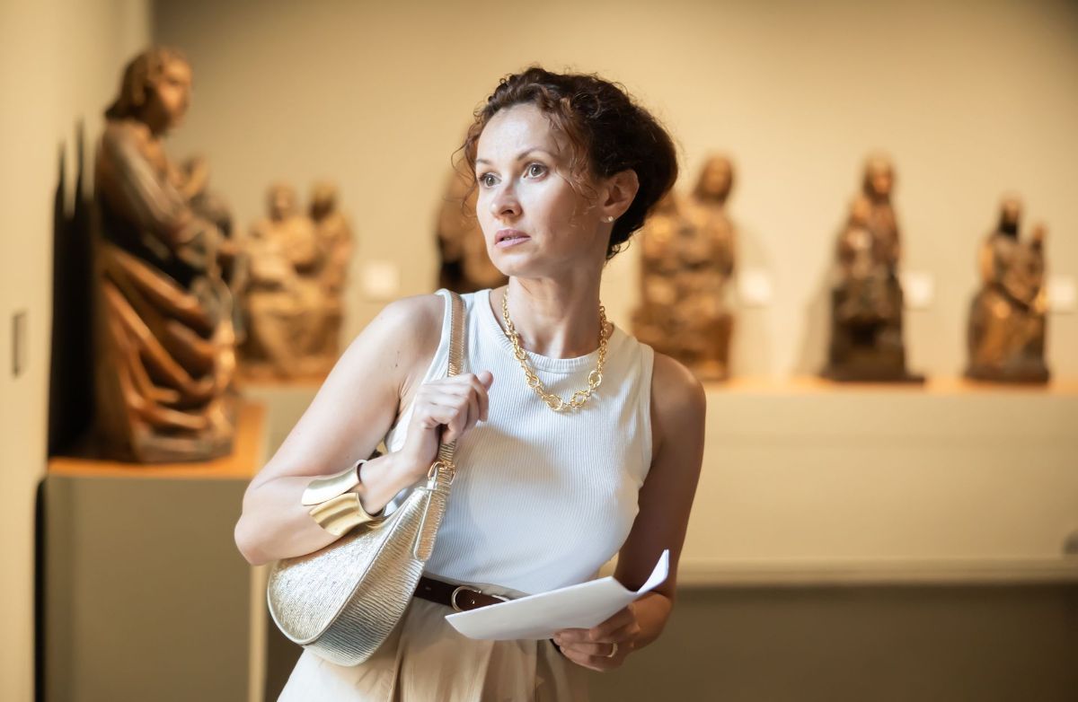 A woman is looking at sculptures in a museum.