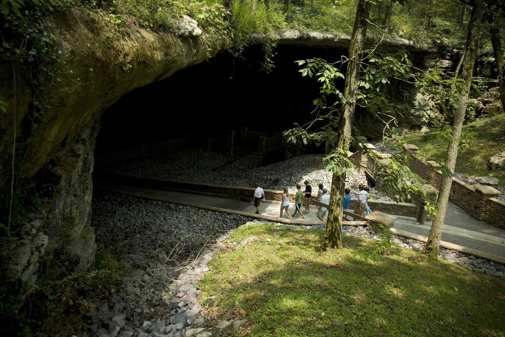A group of people are standing in front of a cave.
