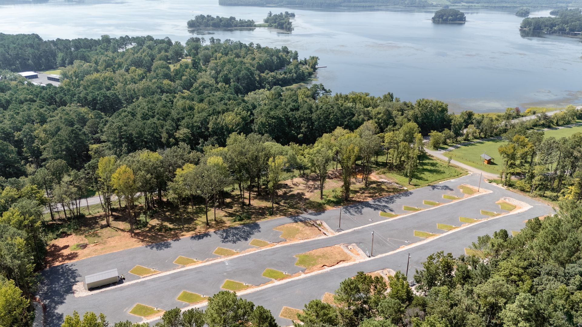 An aerial view of a lake surrounded by trees and a road.