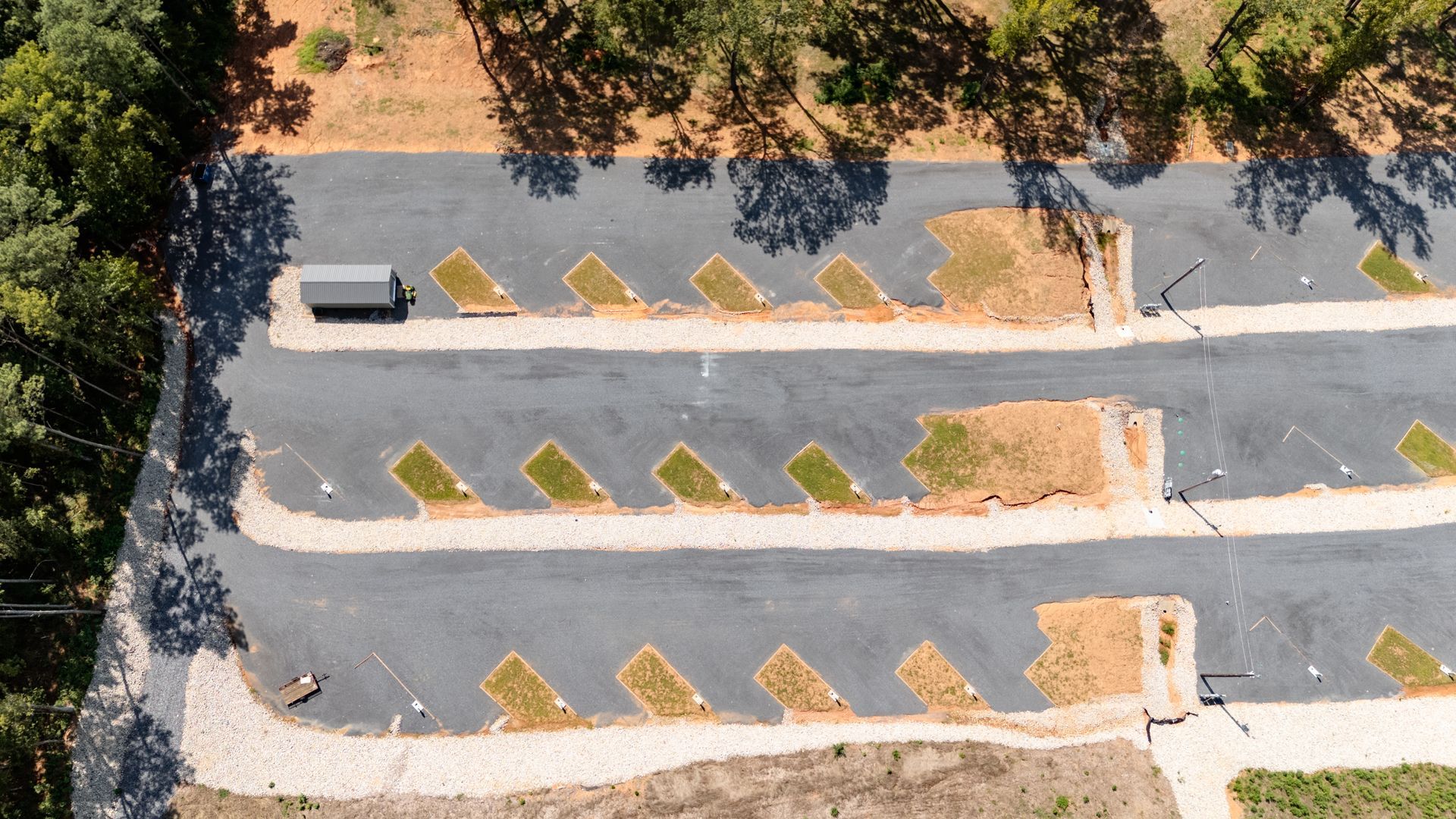 An aerial view of a parking lot with trees in the background