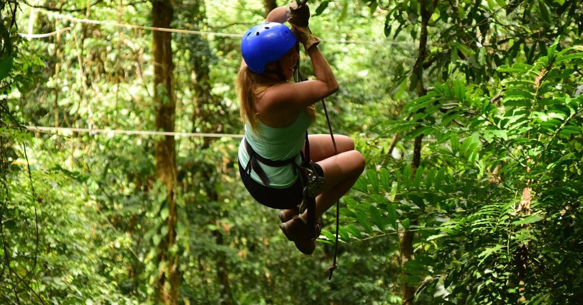A woman is flying through the air on a zip line in the woods.