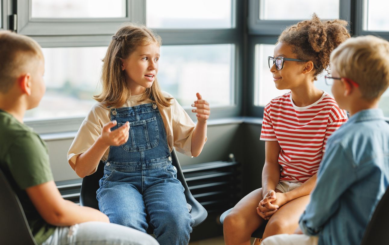 A group of children are sitting in a circle talking to each other.