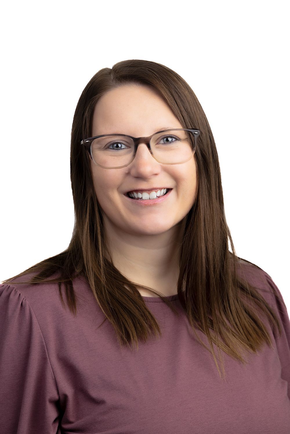 A woman wearing glasses and a grey shirt is smiling for the camera.