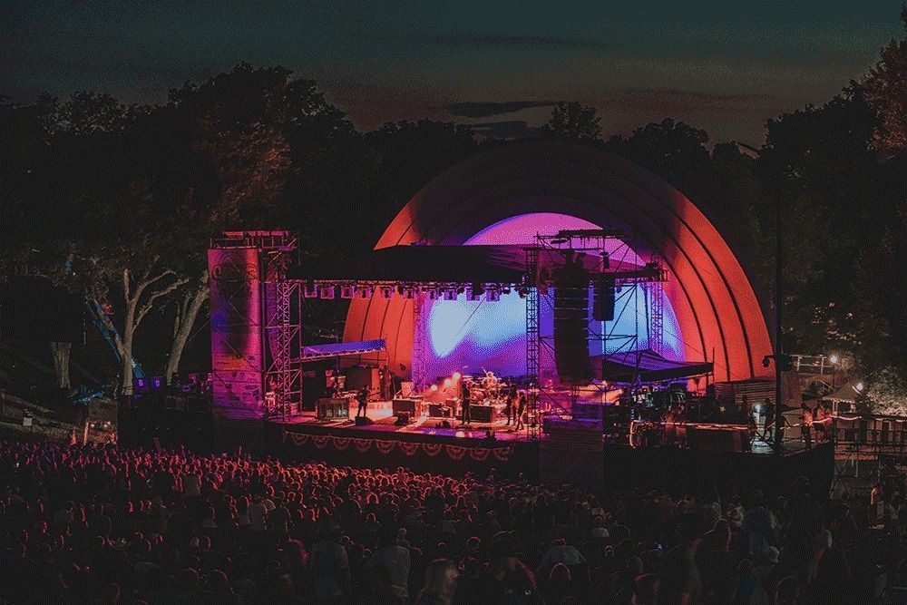 A large crowd of people are watching a concert at night.