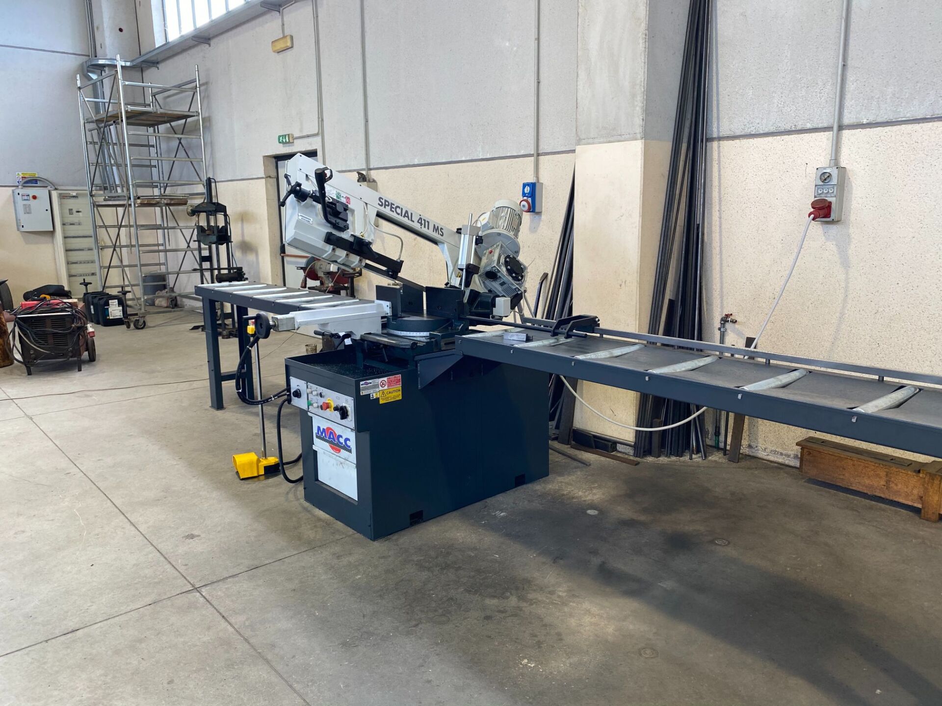 Macchina per la lavorazione dei metalli in un'officina, con lungo nastro trasportatore.