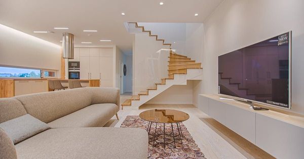 A living room with a couch , television , and stairs.