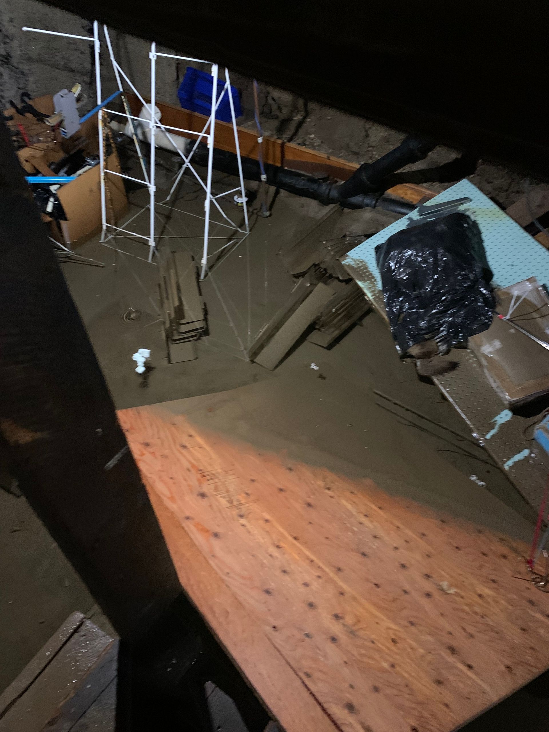 Flooded attic space with debris and a white metal support structure.
