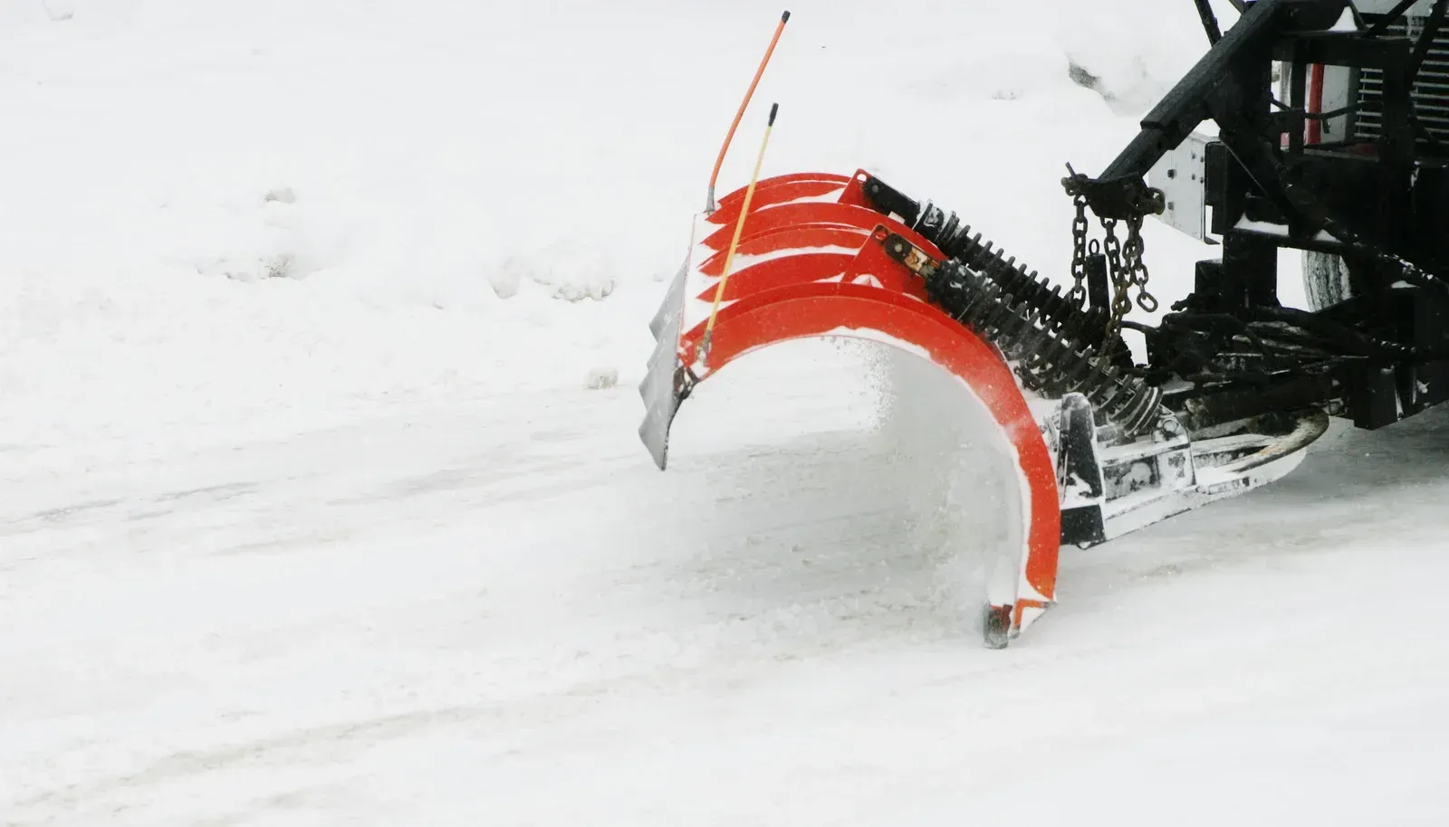 Person shoveling snow from a driveway, another person and a dog in the background.