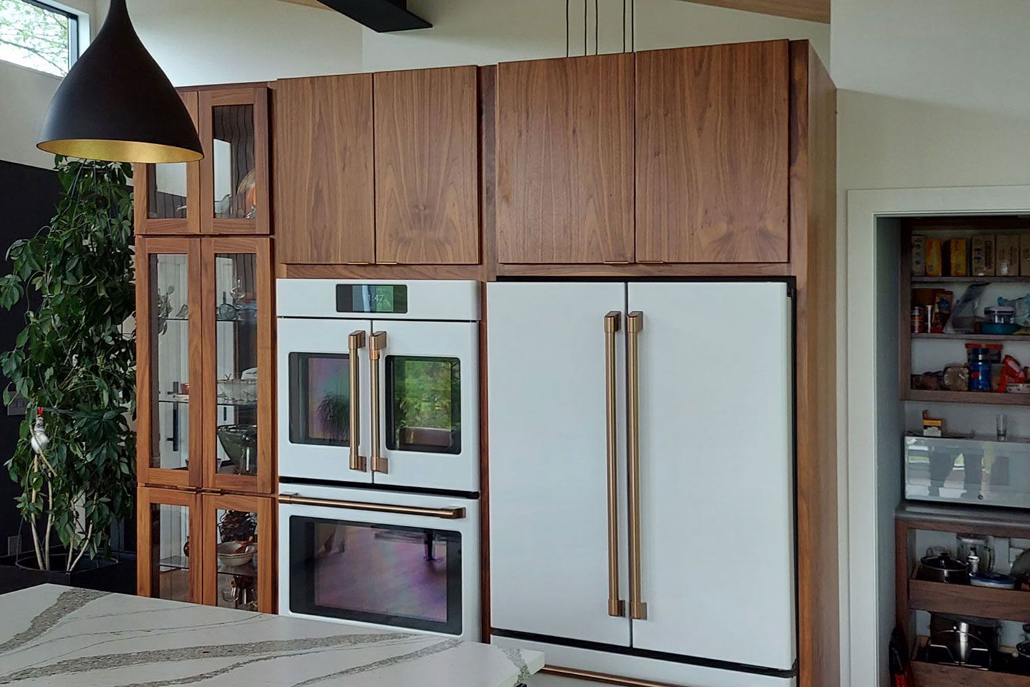 Kitchen with wood cabinets, white appliances, and gold hardware; open shelving visible.