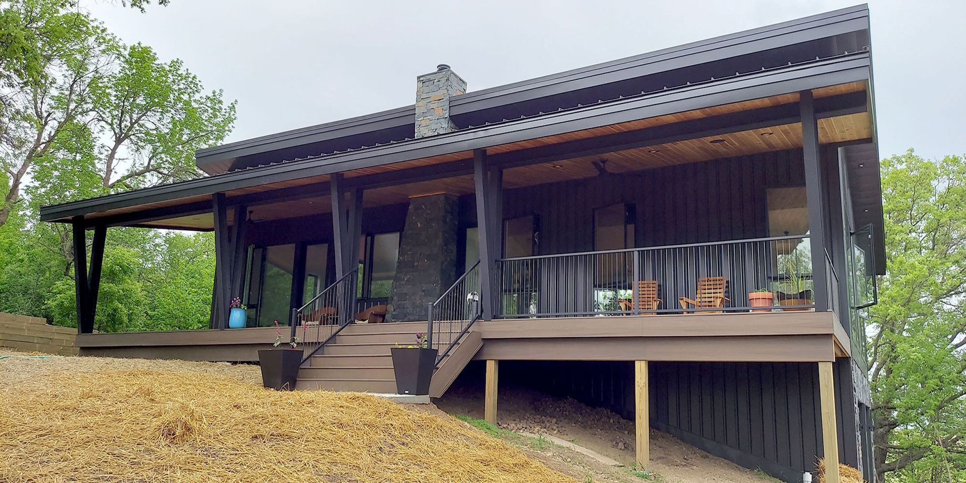 Modern cabin with black trim, chimney, and dark deck.