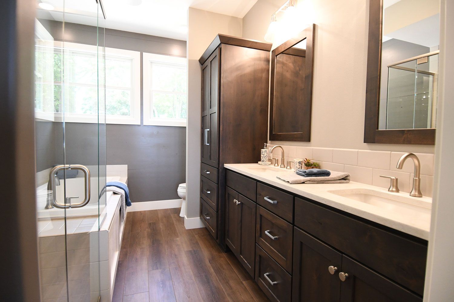 Bathroom with dark brown cabinets, white countertops, and a glass shower.